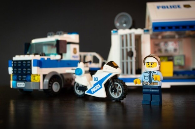 a lego police man figure with police vehicles in the background