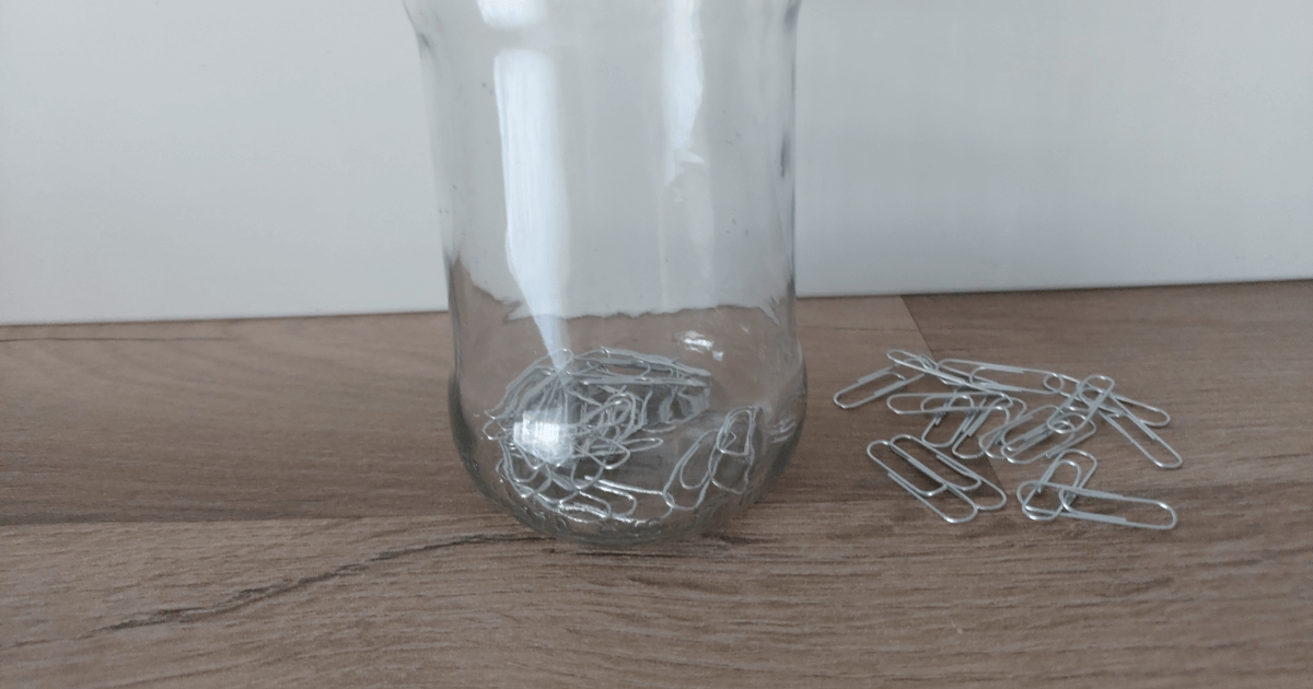 A jar with paper clips in and next to it