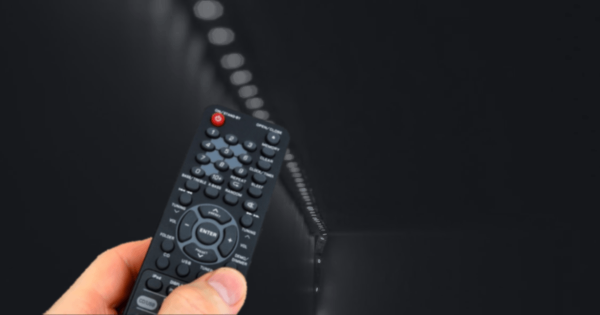 a hand holding a remote control with a led strip in the background